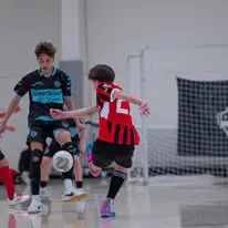 IDLeague11 Kids playing indoor soccer, red and black jerseys.